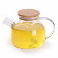 Clear glass teapot with wooden lid on a wooden surface