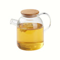 Glass teapot with wooden lid on a wooden surface with tea inside