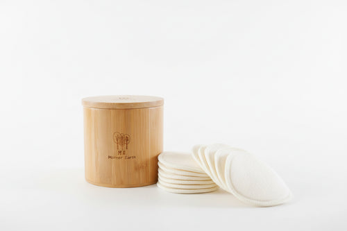 Bamboo container with reusable pads on a light surface with plants in the background