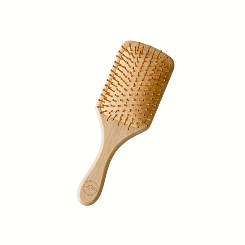 Wooden hairbrush on a marble surface with 'Earth Ahead' branding and decorative elements.
