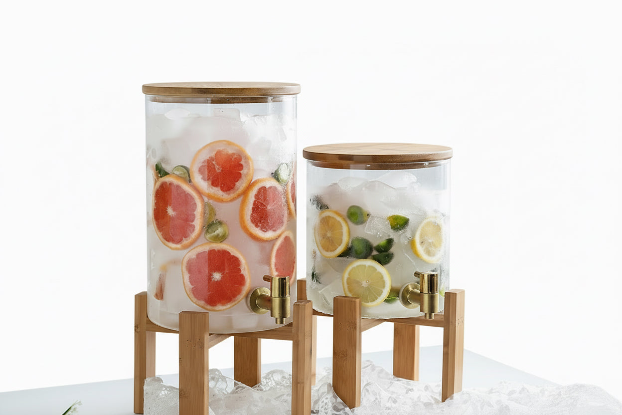 Two glass containers with fruit infusions on stands in a bright room.