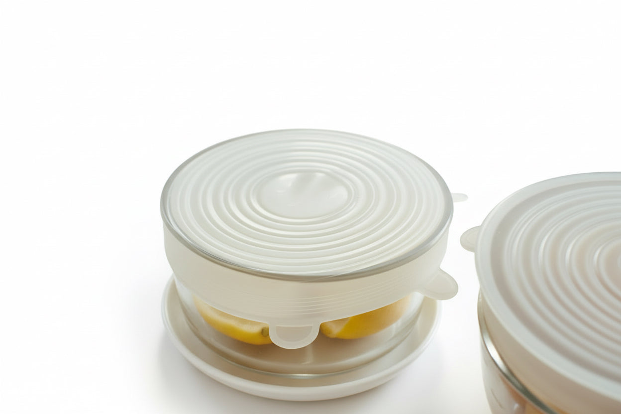Glass container with a silicone lid on a marble surface with orange slices.